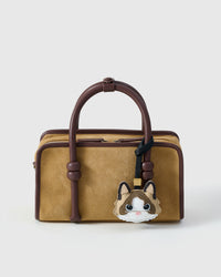 Ragdoll v.1 charm on a tan suede top-handle bag, front — real French leather, made to be carried on the bag that sees every day.