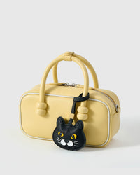 Chubby Midnight British Shorthair on a soft-yellow box bag, side angle — rated 4.9★ by thousands of buyers. Real French Alran leather, 3 days by hand.