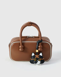 Black long-hair tabby on a tan leather top-handle bag, front view — real French leather, made to be carried on the bag that sees every day.