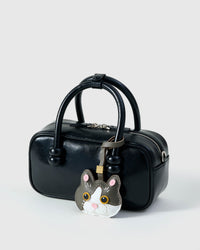 Grey Muse British Shorthair on a glossy black box bag, side angle — loved by thousands of cat lovers. Real French leather, 3 days by hand.