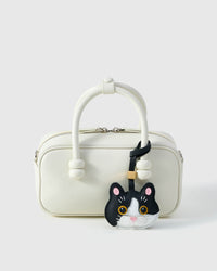 Black Muse British Shorthair styled on a cream box bag, front — a small, specific piece that turns a simple bag into a personal one.