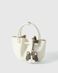 Grey Mist British Shorthair on a cream/ivory bucket bag, side angle — real French leather, 3 days by hand.