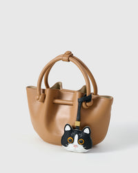 Black Mist British Shorthair on a tan bucket bag, side angle — 5,000+ reviews across STICKYZOO. Real French leather, 3 days by hand.