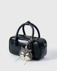 Grump cat charm on a glossy black box bag, side angle — rated 4.9★ by thousands of buyers. Real French Alran leather, 3 days by hand.