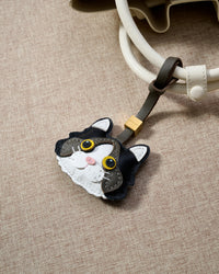 Black Ragdoll charm hanging on cream/ivory bag handles, close detail — loved by thousands of cat lovers. Real French leather, 3 days by hand.