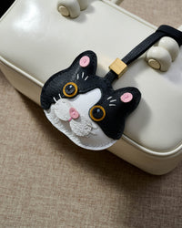 Black Muse British Shorthair hanging on a cream box bag, close angle — rated 4.9★ by thousands of buyers. Real French Alran leather, 3 days by hand.