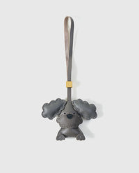 Handmade sitting Poodle Puppy leather bag charm by STICKYZOO — hand-cut, hand-stitched, hand-layered French Alran goatskin over 3 days in gray. Full-body design. Designed in Amsterdam.