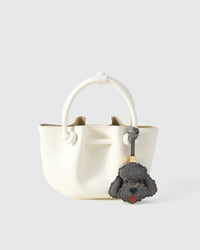 Close-up of handmade Poodle leather bag charm — hand-stitched visible edges on French Alran goatskin, 18K gold-plated cube hardware. STICKYZOO.