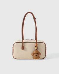 Close-up of handmade Poodle leather bag charm — hand-stitched visible edges on French Alran goatskin, 18K gold-plated cube hardware. STICKYZOO.