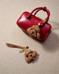 Handmade Poodle leather bag charm styled on a handbag — French Alran goatskin, 18K gold-plated hardware. STICKYZOO Amsterdam design.