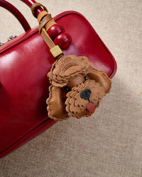 Poodle leather bag charm in both attachment formats — leather strap with engraved 18K gold cube and 18K gold-plated keychain clip. Handmade French Alran goatskin.