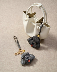 Close-up of handmade Poodle leather bag charm — hand-layered topknot curls in French Alran goatskin, hand-stitched edges. STICKYZOO Amsterdam design.