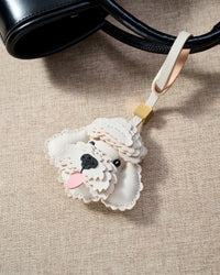 Close-up of handmade Poodle leather bag charm — hand-stitched visible edges on French Alran goatskin, 18K gold-plated cube hardware. STICKYZOO.