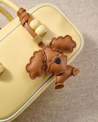 Close-up of handmade Poodle leather bag charm — hand-layered topknot curls in French Alran goatskin, hand-stitched edges. STICKYZOO Amsterdam design.