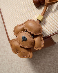 Close-up of handmade Poodle leather bag charm — hand-layered topknot curls in French Alran goatskin, hand-stitched edges. STICKYZOO Amsterdam design.