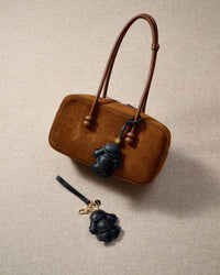 Close-up of handmade Poodle leather bag charm — hand-stitched visible edges on French Alran goatskin, 18K gold-plated cube hardware. STICKYZOO.
