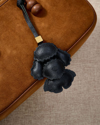 Close-up of handmade Poodle leather bag charm — hand-layered topknot curls in French Alran goatskin, hand-stitched edges. STICKYZOO Amsterdam design.