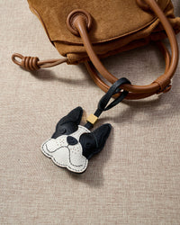 Close-up of handmade French Bulldog leather bag charm — hand-stitched visible edges on French Alran goatskin, 18K gold-plated cube hardware. STICKYZOO.