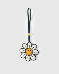 STICKYZOO Smile Flower Charm — white French Alran goatskin petals with golden smiley face centre and dark border, 18K gold-plated hardware. 3-day handmade piece.