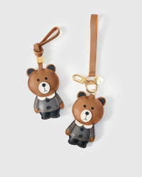Both editions of the teddy bear charm — leather strap loop for bags, or 18K gold-plated keychain clip.