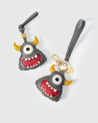 Both editions of the little monster — leather strap loop for bags, or 18K gold-plated keychain clip.
