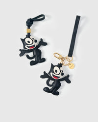 Both editions of the cartoon cat charm side by side — leather strap loop for bags, or 18K gold-plated keychain clip with engraved STICKYZOO disc.