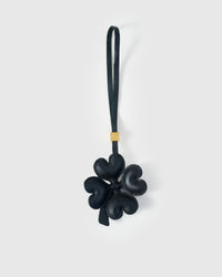 STICKYZOO Lucky Clover Charm in black French Alran goatskin — four padded heart-shaped petals in a sculptural 3D form, gold-plated hardware. 3-day handmade piece.