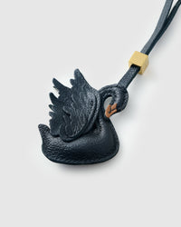 Close-up of handmade leather swan bag charm — full-grain French Alran goatskin, hand-stitched edges, 18K gold-plated cube hardware. STICKYZOO 3-day artisan build.