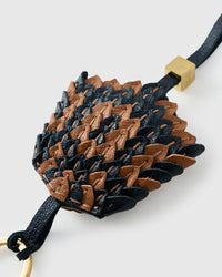 Tight detail of the black-and-caramel scales — French Alran goatskin, each panel cut and placed by hand.