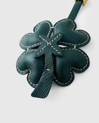 STICKYZOO Lucky Clover Charm clipped to a handbag — handmade French Alran goatskin in forest green padded 3D. 3-day artisan build.