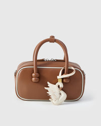 Handmade leather swan bag charm clipped to a handbag — full-grain French Alran goatskin, hand-layered and hand-stitched. STICKYZOO handmade leather charm, designed in Amsterdam.