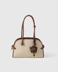 Scaled charm in black + caramel styled on a bag — a small, specific piece that turns a simple bag into a personal statement.