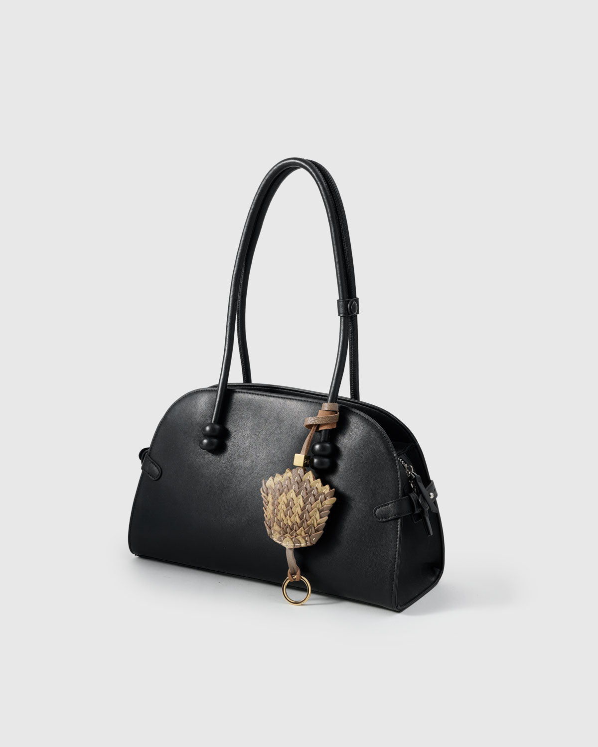 Both editions of the scaled charm — leather strap for bags, or 18K gold-plated keychain clip.