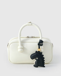 Black dinosaur charm styled on a bag — a small, specific piece that turns a simple bag into a personal one.