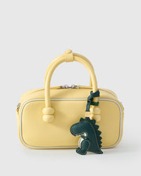 Green dinosaur charm styled on a bag — a small, specific piece that turns a simple bag into a personal one.