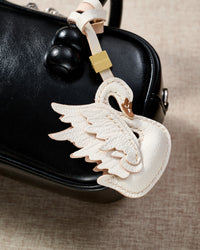 Close-up of handmade leather swan bag charm — hand-layered wing feathers in full-grain French Alran goatskin, no machine work. STICKYZOO 3-day artisan build.