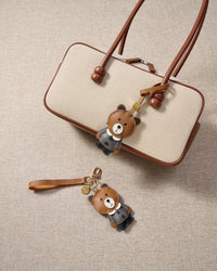 Close-up of the teddy bear charm — hand-cut and hand-stitched panels of French Alran goatskin. Every layer by hand.
