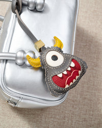 Little monster charm styled on a bag — a small, specific piece that turns a simple bag into a personal one.