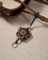 Close-up — every scale cut and layered by hand in black and caramel goatskin.