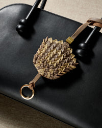 Scaled gray-and-gold charm — real French leather, five days by hand.