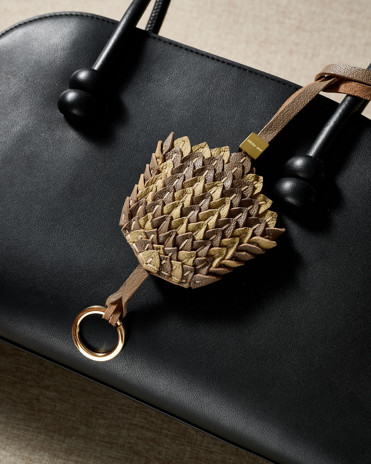 Scaled gray-and-gold charm — real French leather, five days by hand.