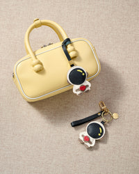 Both editions of the astronaut charm — leather strap loop for bags, or 18K gold-plated keychain clip.