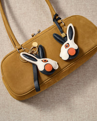 Both editions of the rabbit charm — leather strap loop for bags, or 18K gold-plated keychain clip.
