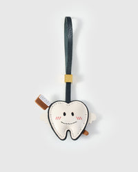 Tooth fairy charm handmade from French Alran genuine goatskin — white tooth body with stitched smile, red blush marks, cream leather wings, toothbrush detail, navy leather strap. Three days by hand. Arrives in luxury gift packaging. Designed in Amsterdam.