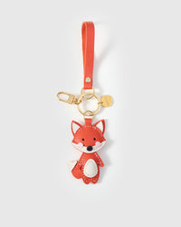 Both editions of the fox charm — leather strap loop for bags, or 18K gold-plated keychain clip.