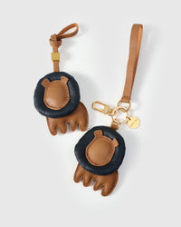 Both editions of the lion charm — leather strap loop for bags, or 18K gold-plated keychain clip.