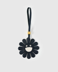 STICKYZOO Night Flower Charm — black French Alran goatskin petals with cream smiley face centre, gold-plated hardware. 3-day handmade piece.
