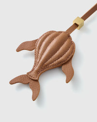 Both editions of the caramel whale — leather strap loop for bags, or 18K gold-plated keychain clip.