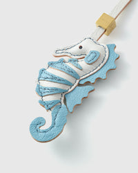 Blue seahorse charm on a bag, side angle — 5,000+ reviews across STICKYZOO. Real French leather, 3 days by hand.