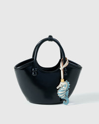 Blue seahorse charm styled on a bag, front — a small, specific piece that turns a simple bag into a personal one.